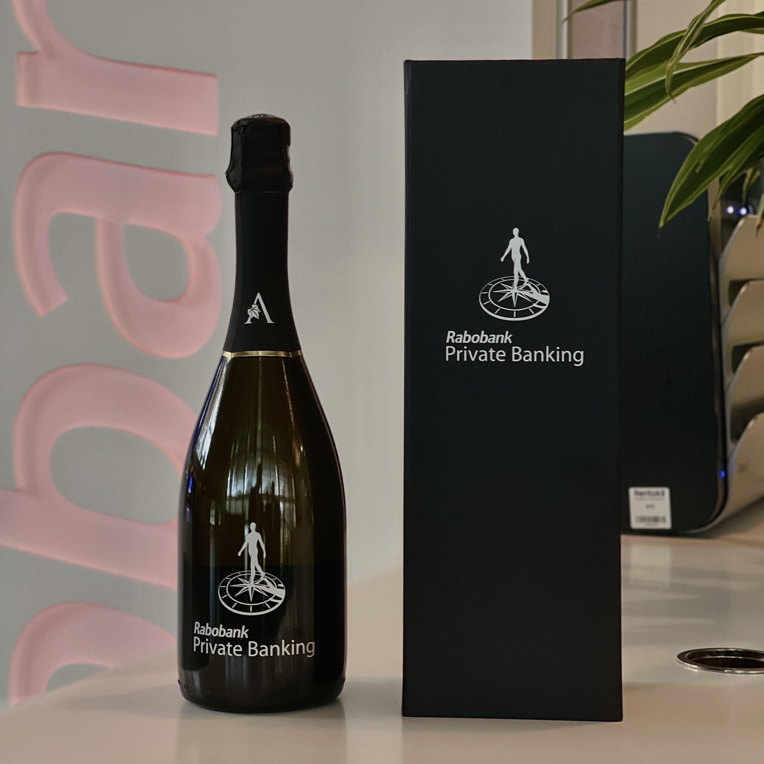 Fles en verpakking van Rabobank Private Banking champagne op een bureau.